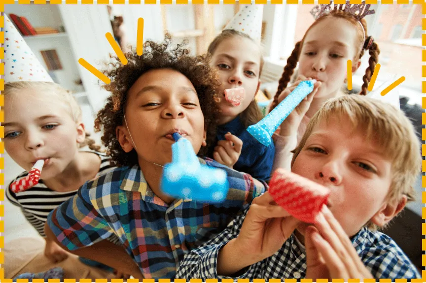 Kinder pusten bei einer Geburtstagsfeier lachend in Partytröten