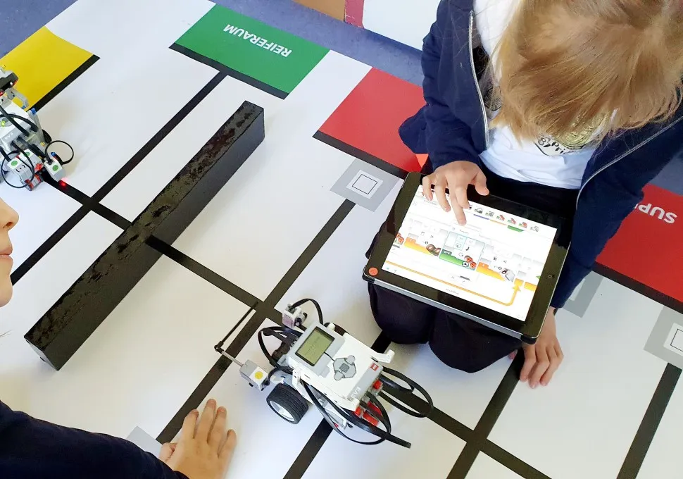 Kinder programmieren einen LEGO-Roboter auf dem Fahr-Parcours