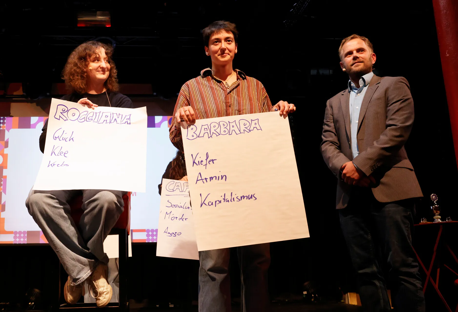Kopf-an-Kopf-Rennen: Slammerinnen mit Zetteln zu ihren Themen und der Moderator