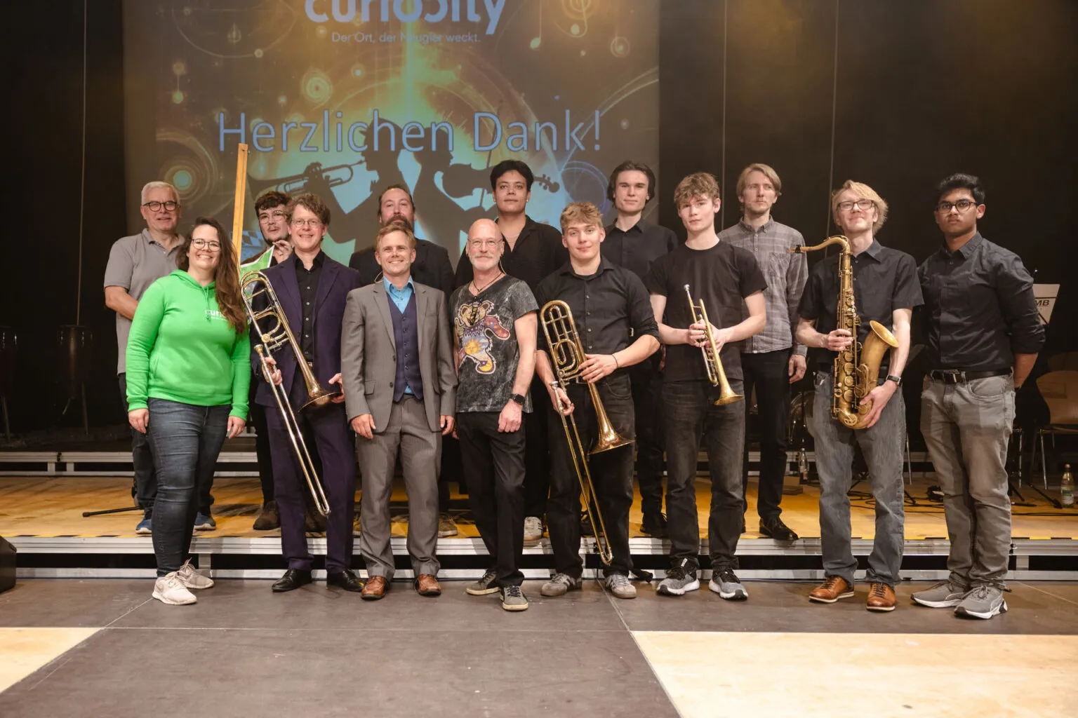 Gruppenfoto des Teams und der Band auf der Bühne