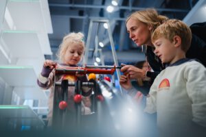 Kinder mit Mutter lassen Holzkugeln auf kurzen Bahnen um die Wette laufen