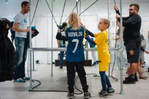 Vier Menschen heben über vier Seile gemeinsam ein kleines Gewicht an